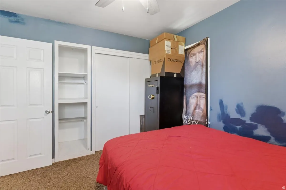 Bedroom with carpet flooring, a ceiling fan, and built-in shelving