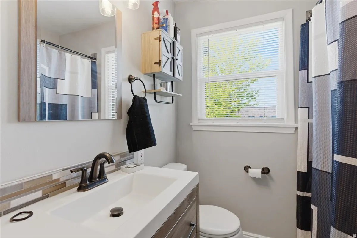 Contemporary bathroom featuring a single white basin, dark bronze faucet, and a mosaic tile backsplash