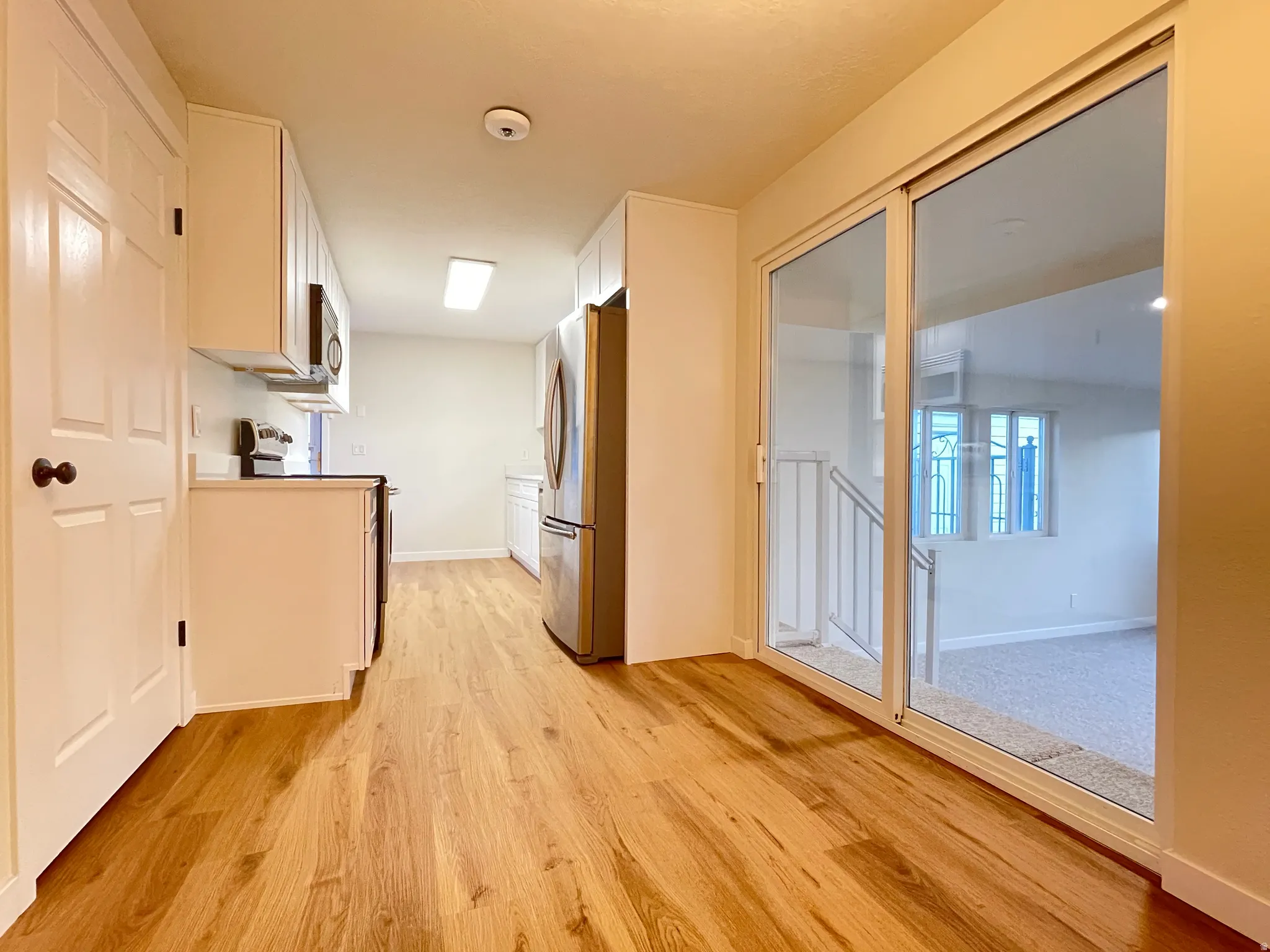 Kitchen featuring wood-finish flooring, white cabinetry, and stainless steel appliances