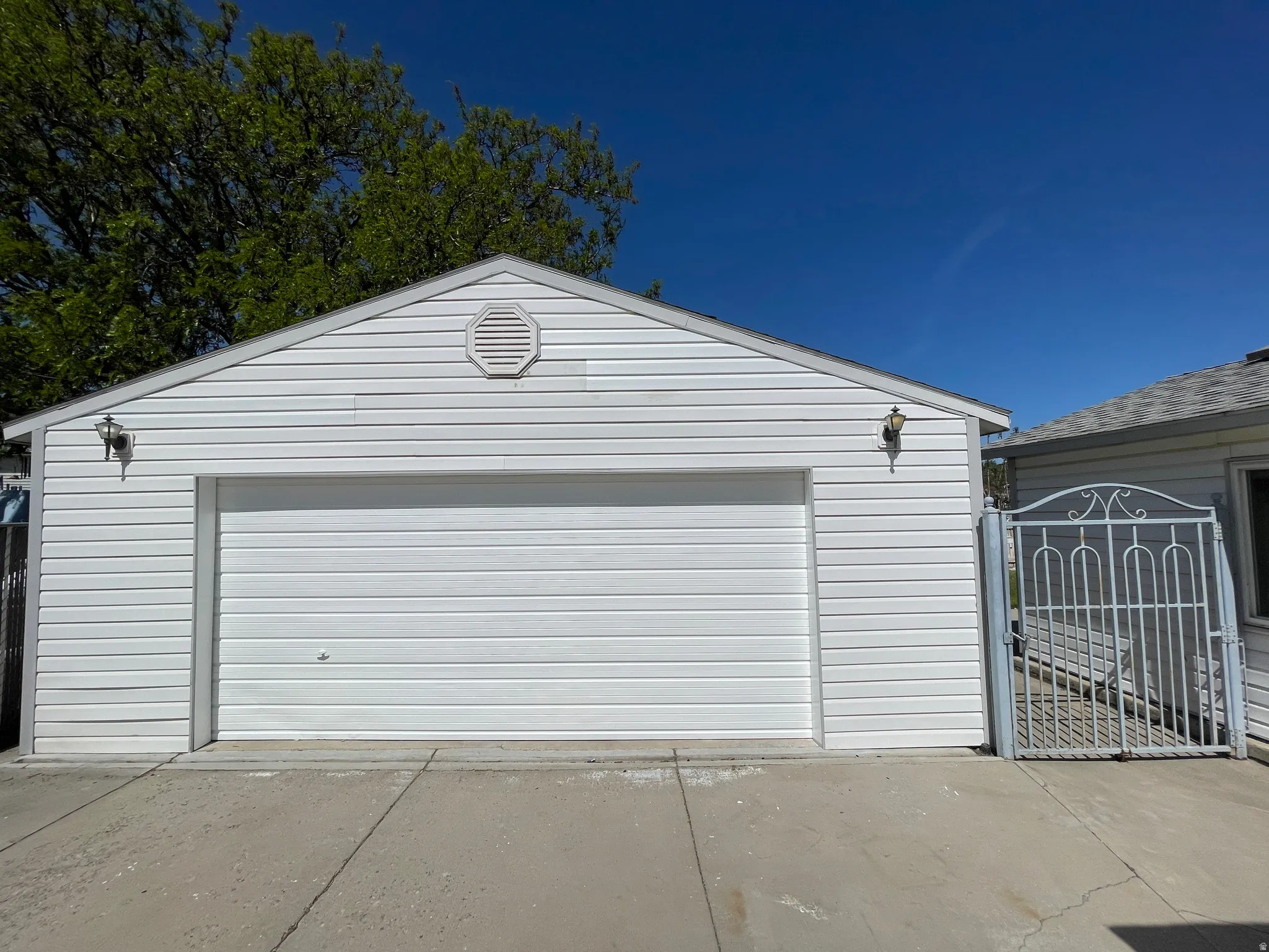 Detached garage with white horizontal siding and a matching overhead door