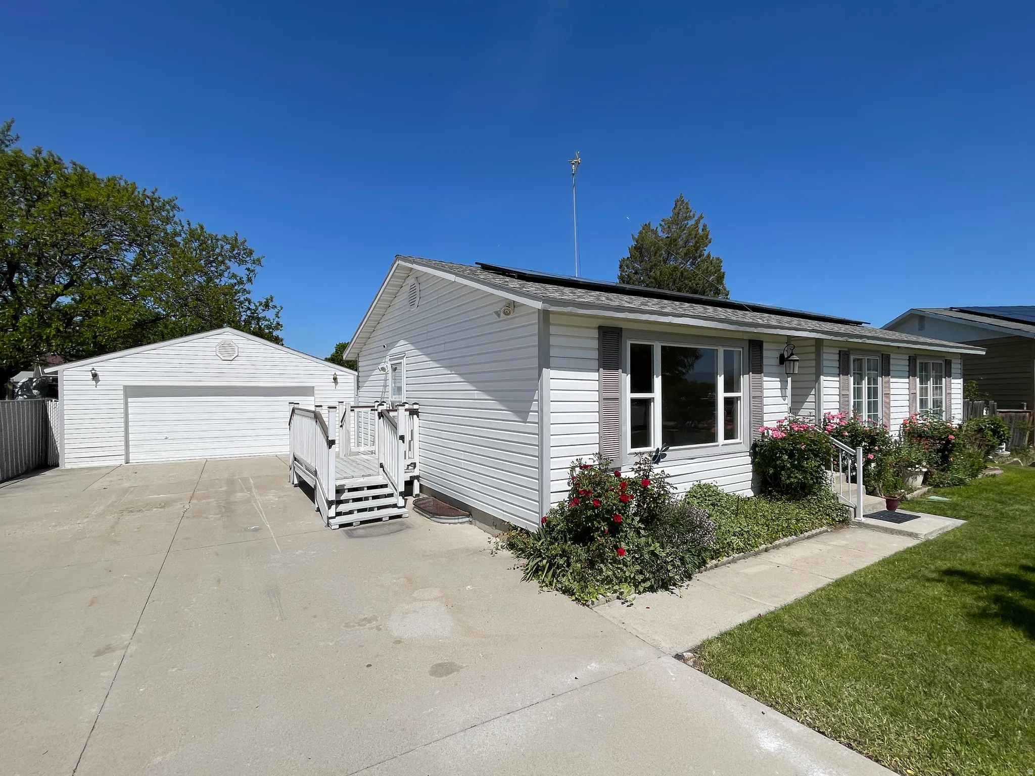 White siding exterior with a concrete driveway and an attached deck