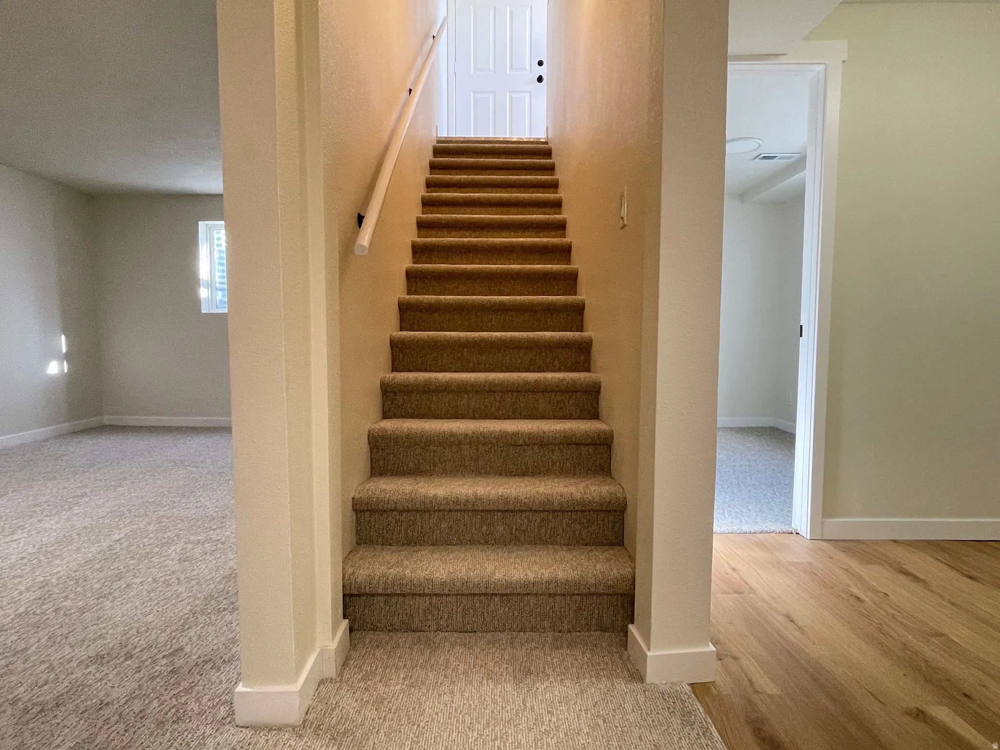 Stairway leading to upstairs, to left a peak into the living room and to the right a peak into the laundry room and bedroom #6