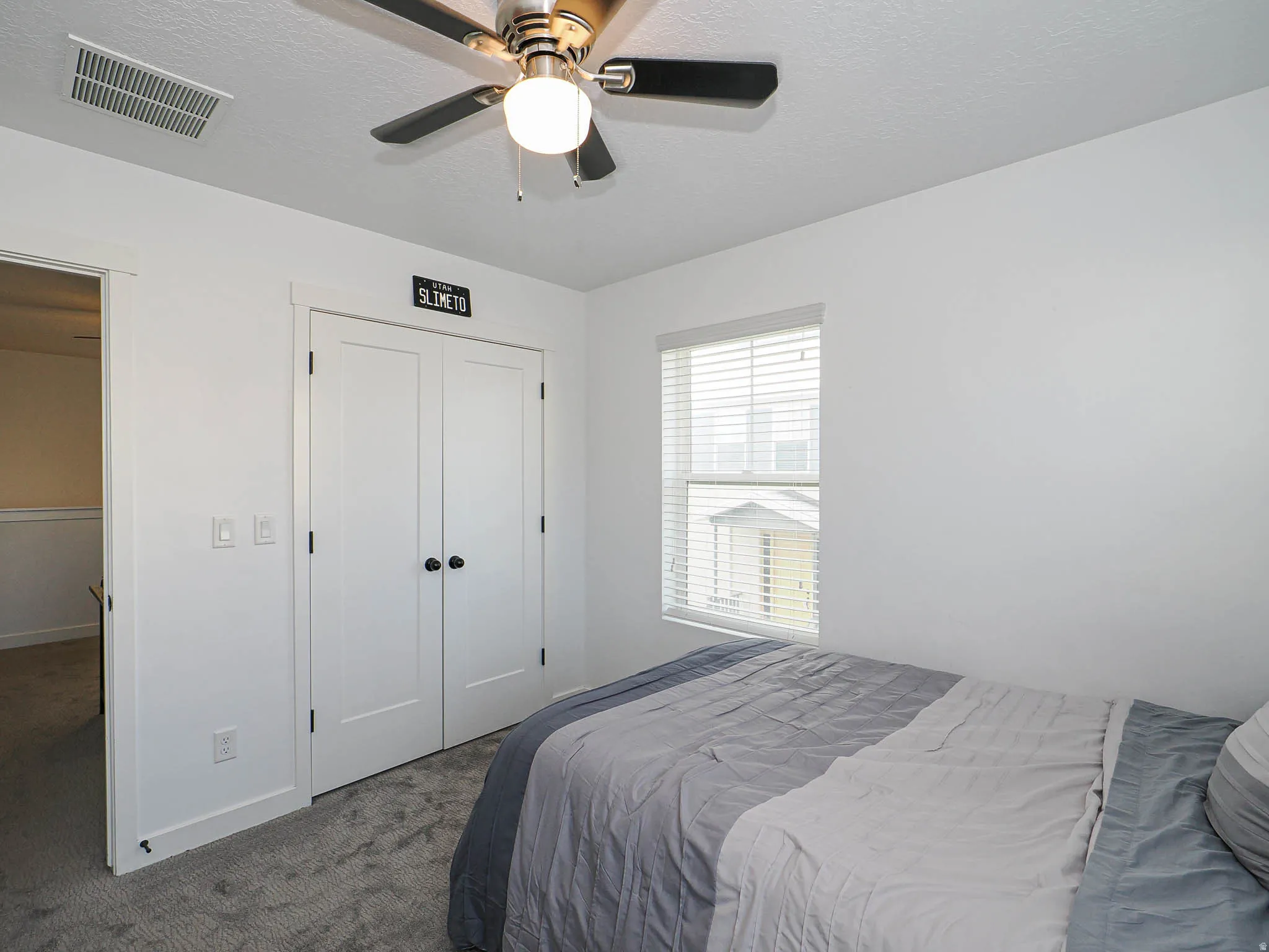 Carpeted bedroom with a textured ceiling, a ceiling fan, and a closet