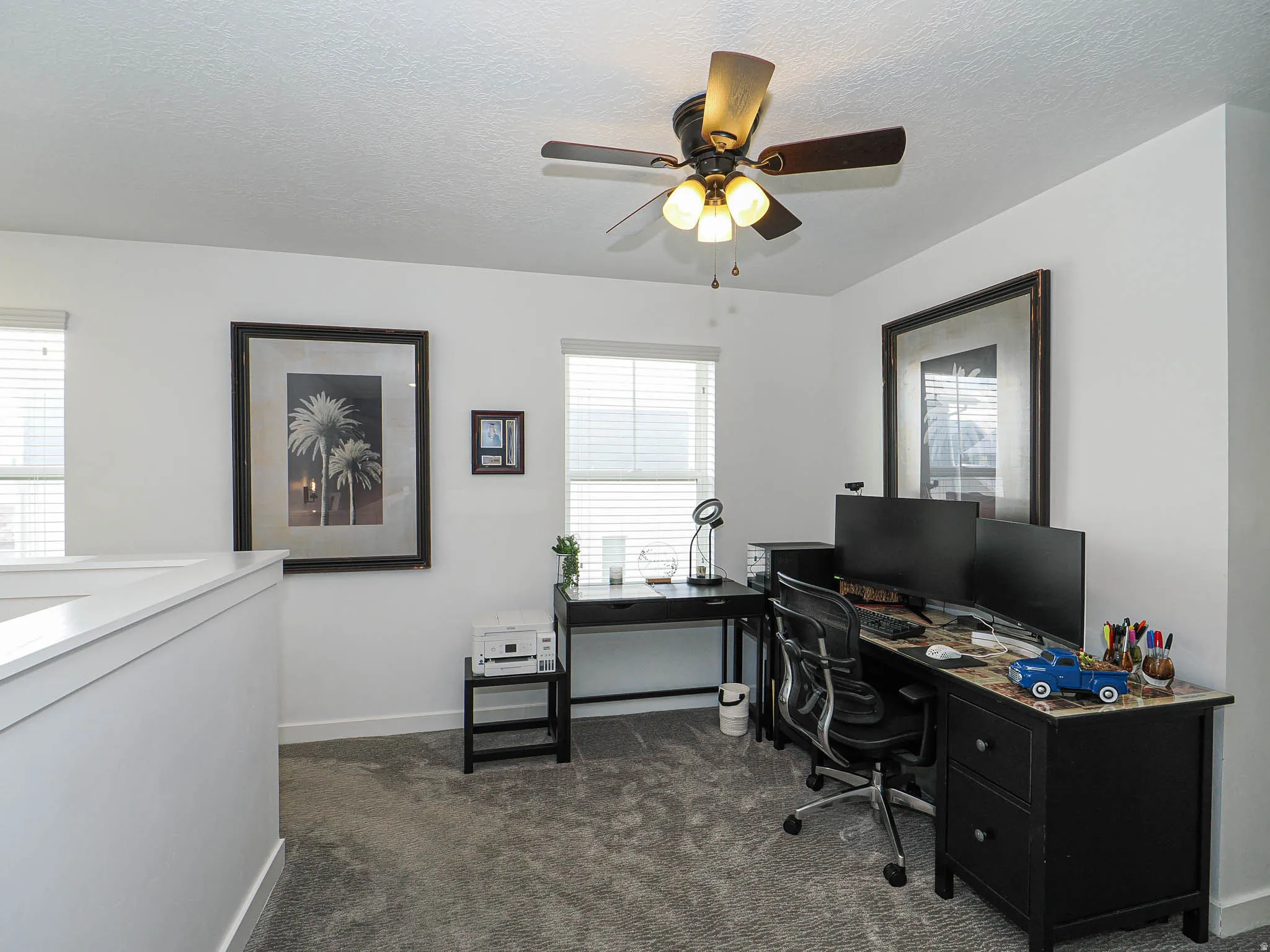 Office space featuring dark carpet, a textured ceiling, and a ceiling fan