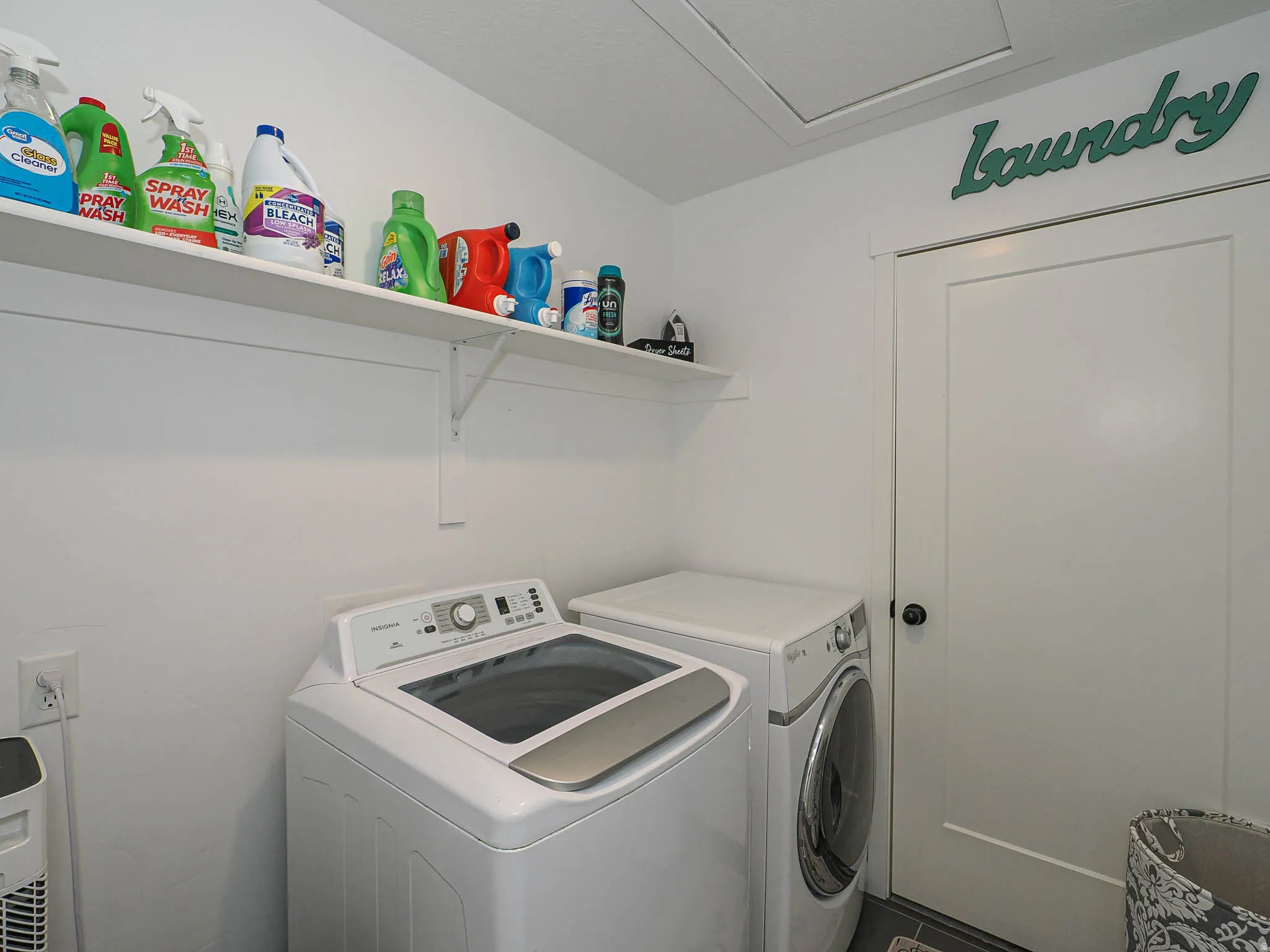 Dedicated laundry area featuring white walls, an overhead storage shelf, and a white door with a black knob