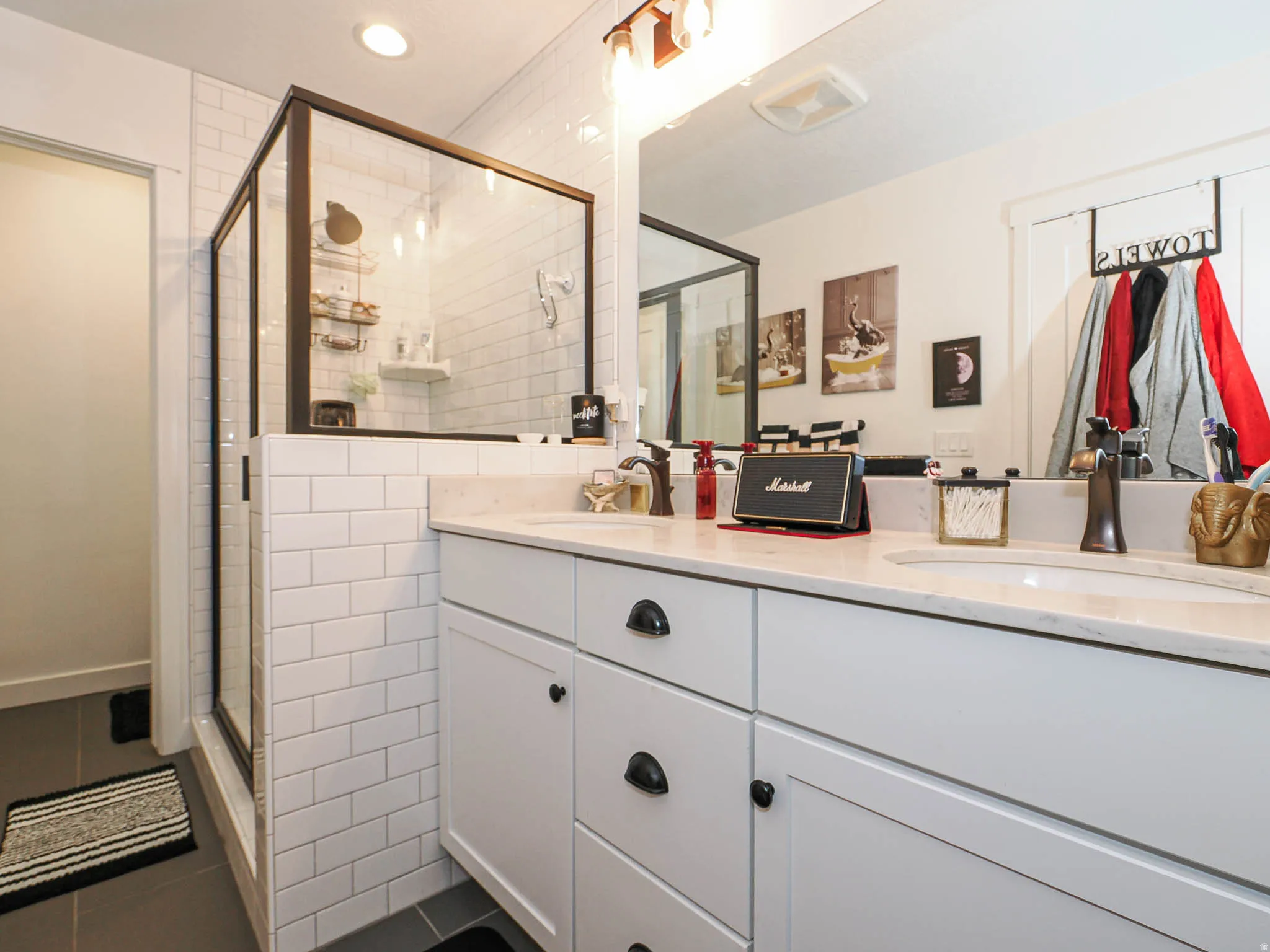 Full bath featuring double vanity, dark tile patterned flooring, a shower stall, and tile walls