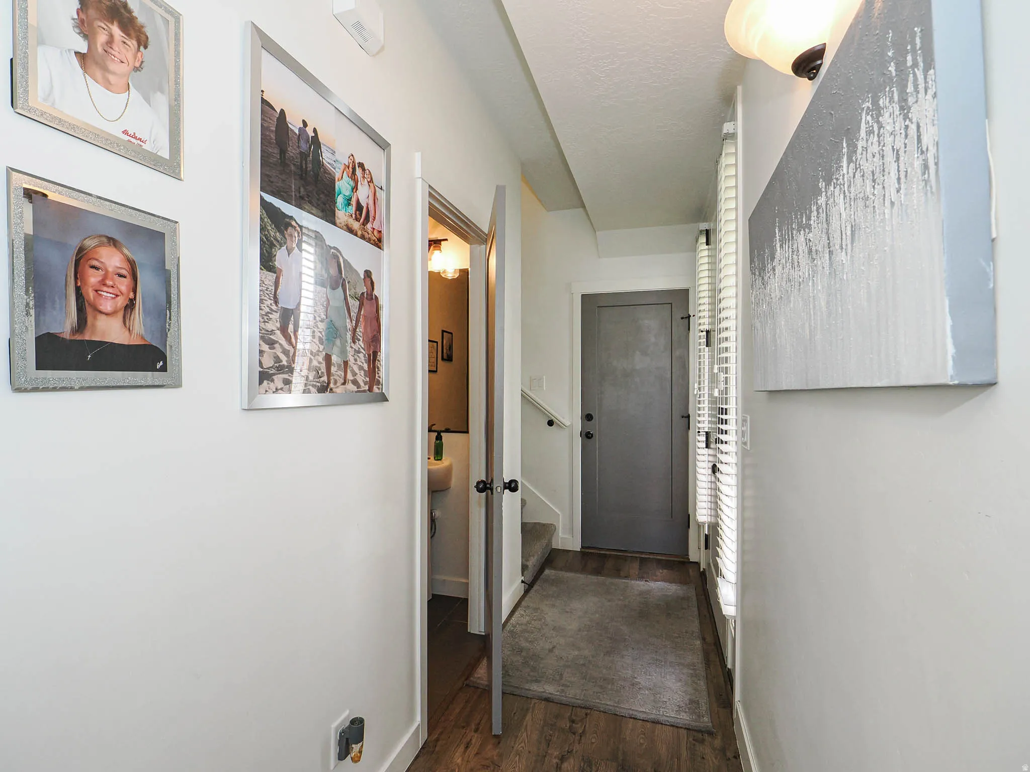 Entryway featuring wood-finish flooring, white walls, and a gray door with black hardware