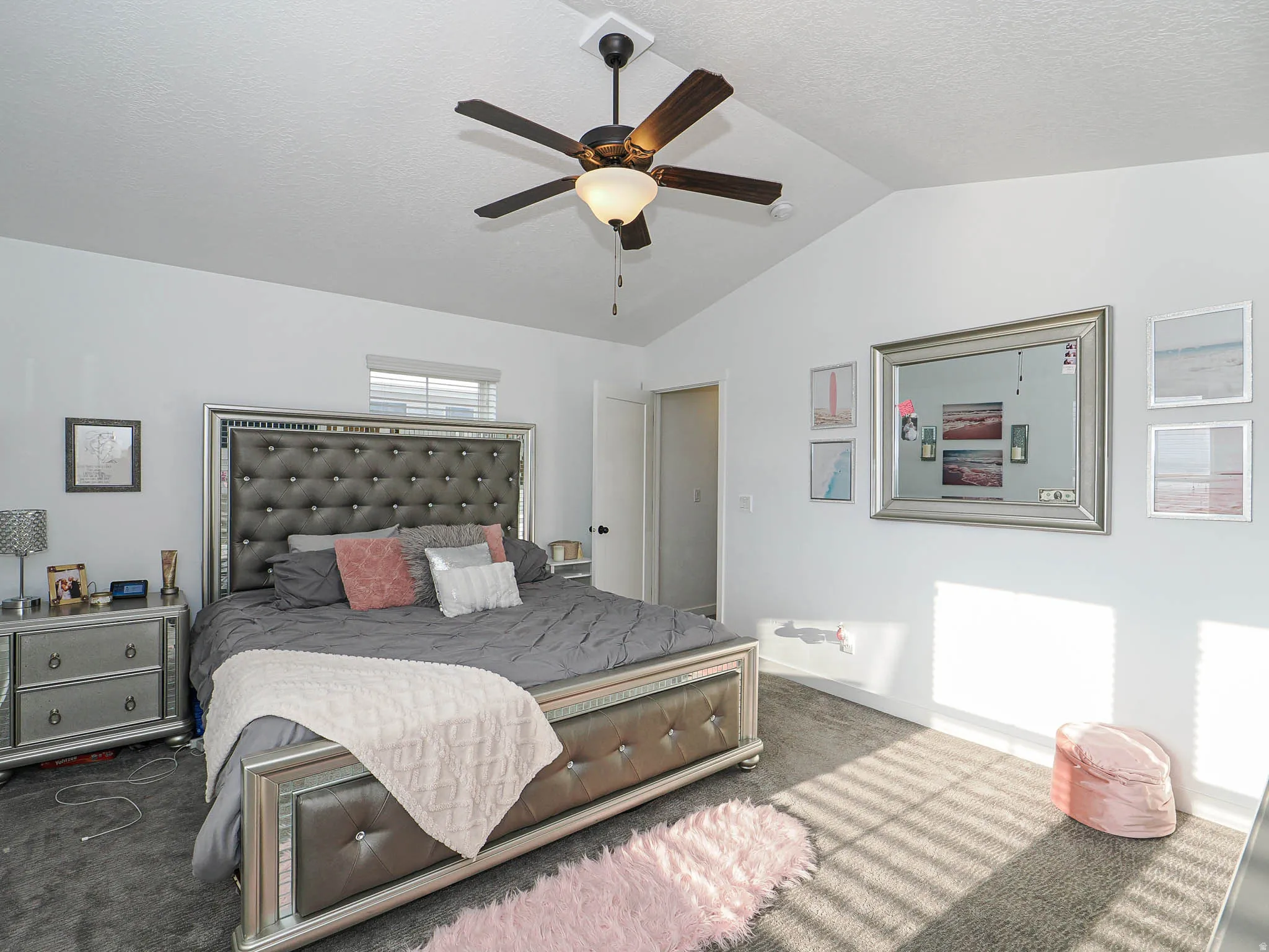 Bedroom with carpet floors, vaulted ceiling, a ceiling fan, and a textured ceiling