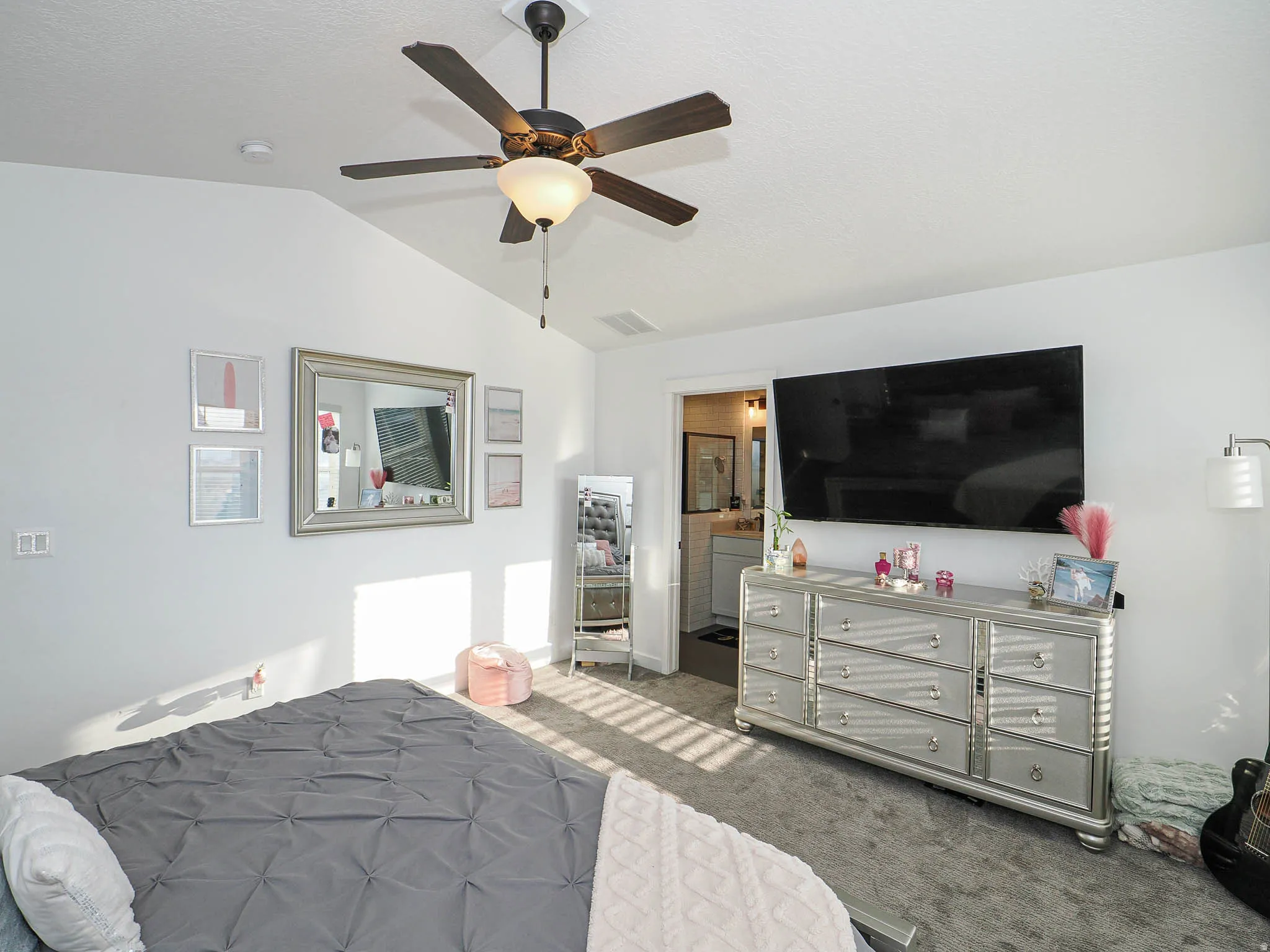 Bedroom with lofted ceiling, carpet floors, a ceiling fan, and ensuite bathroom