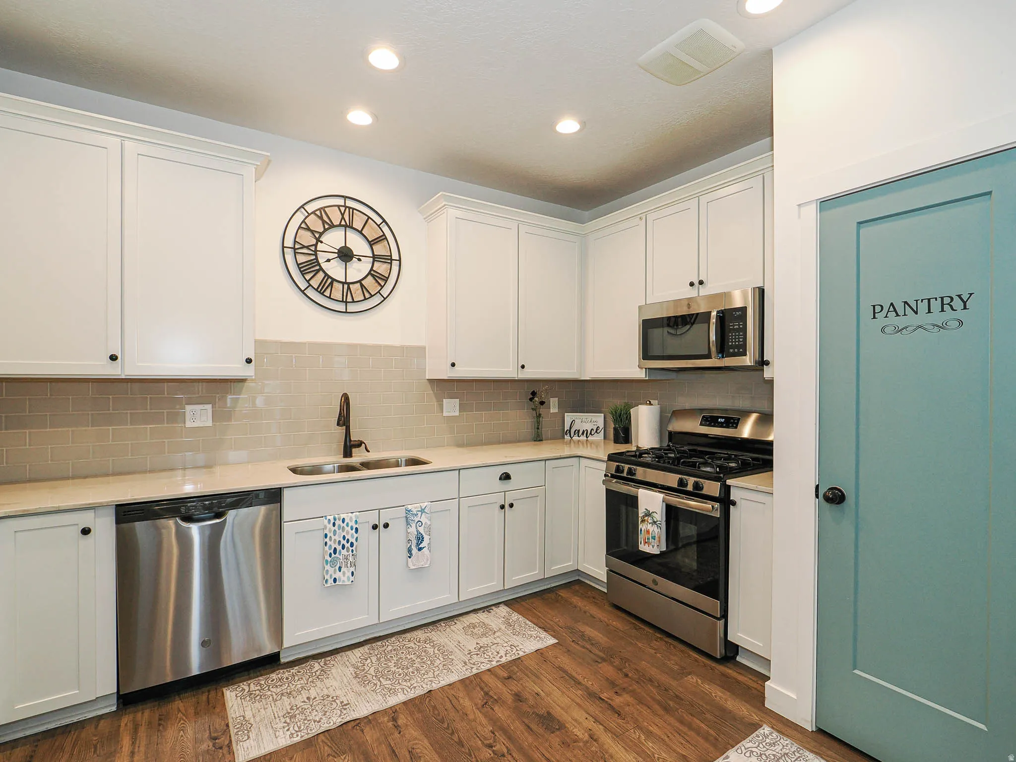 Modern kitchen featuring white shaker cabinetry, light-toned countertops, and a subway tile backsplash
