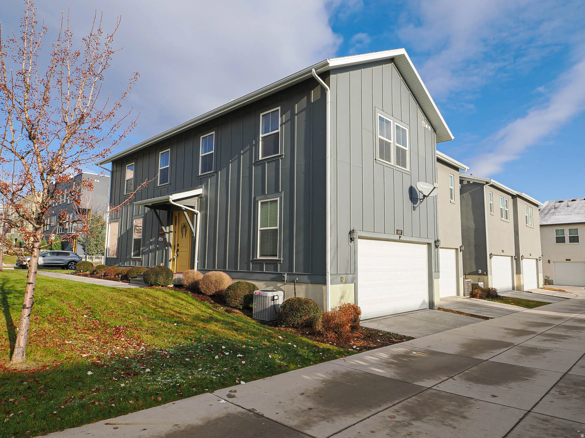 View of front of property featuring an attached garage, a front lawn, board and batten siding, and driveway