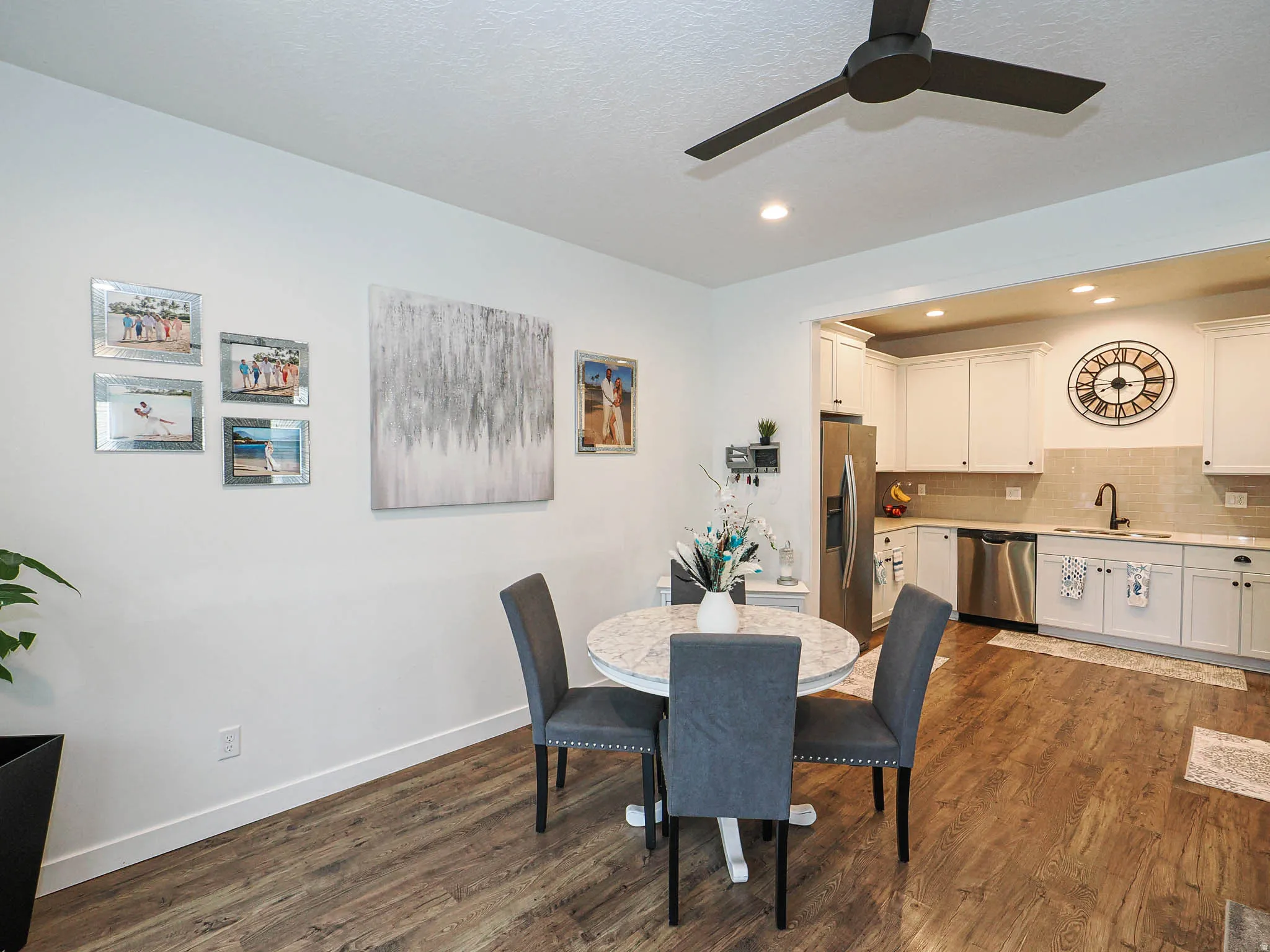 Open-concept kitchen and dining area featuring wood-finish flooring, recessed lighting, and a dark-toned ceiling fan