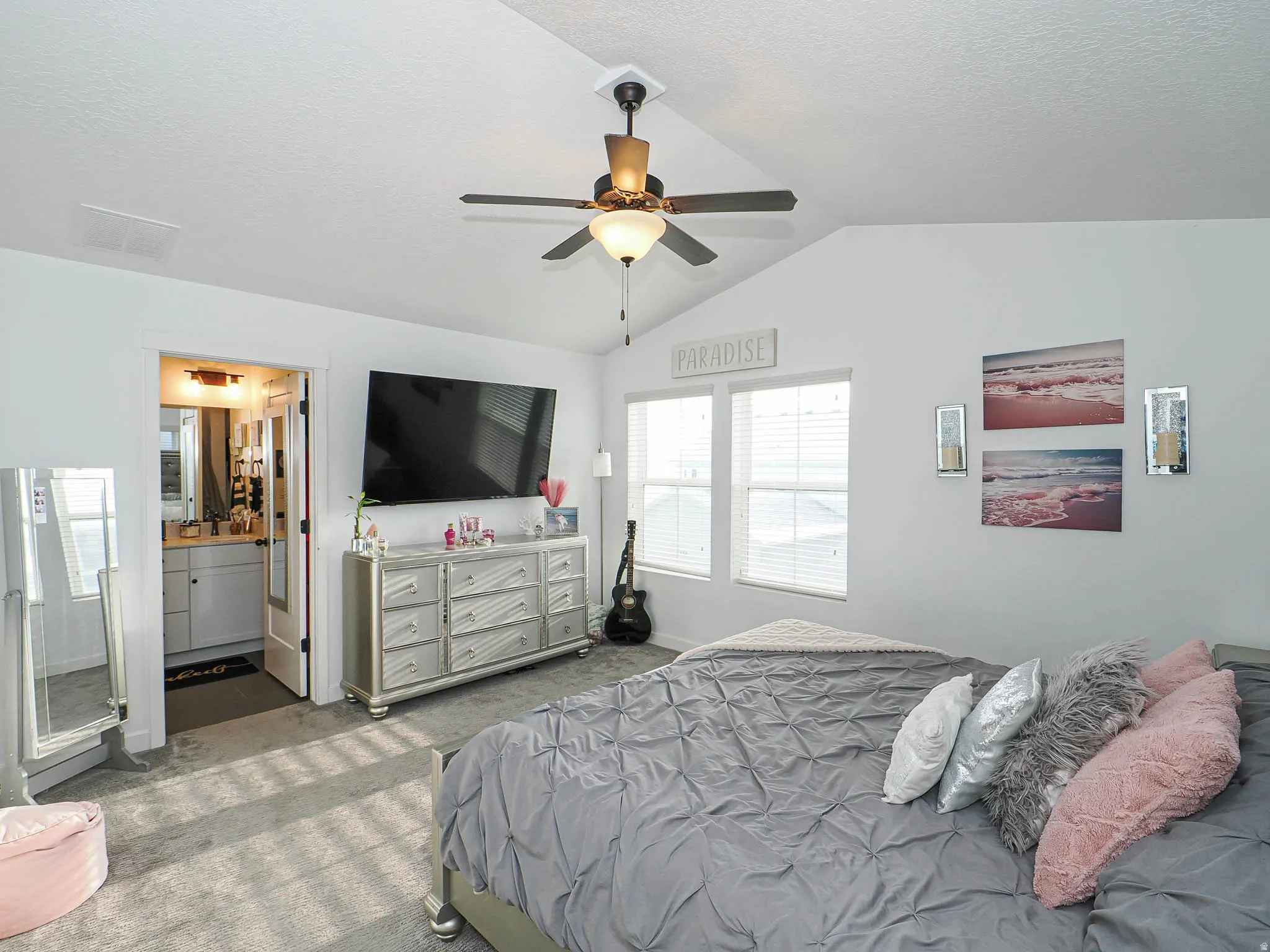 Bedroom with carpet, a ceiling fan, lofted ceiling, a textured ceiling, and connected bathroom