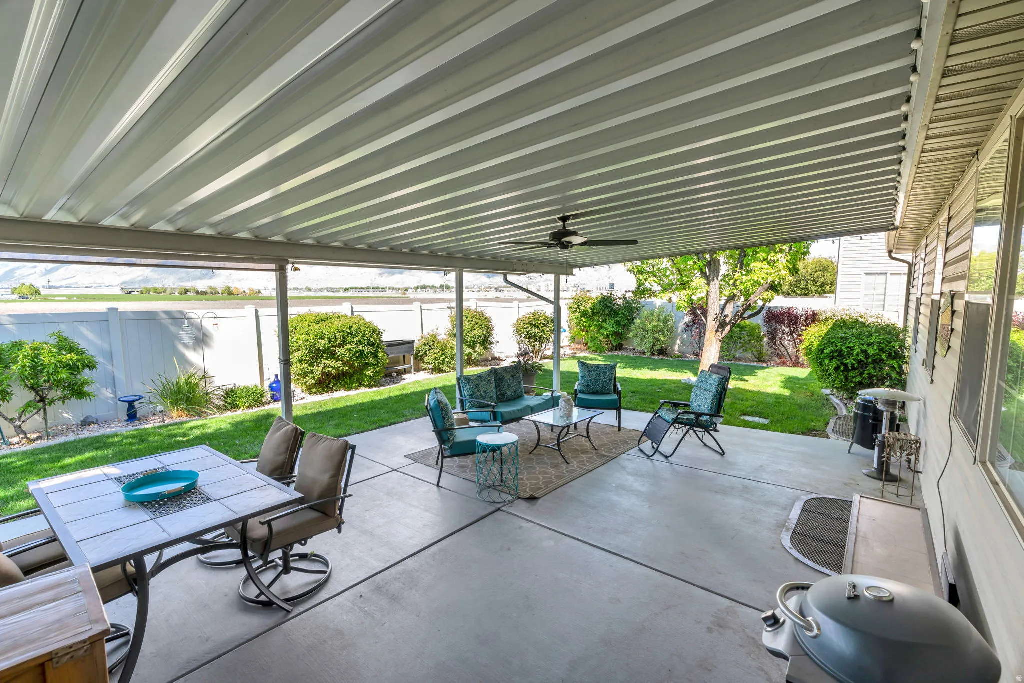 Fenced backyard with a patio area, outdoor dining area, and ceiling fan