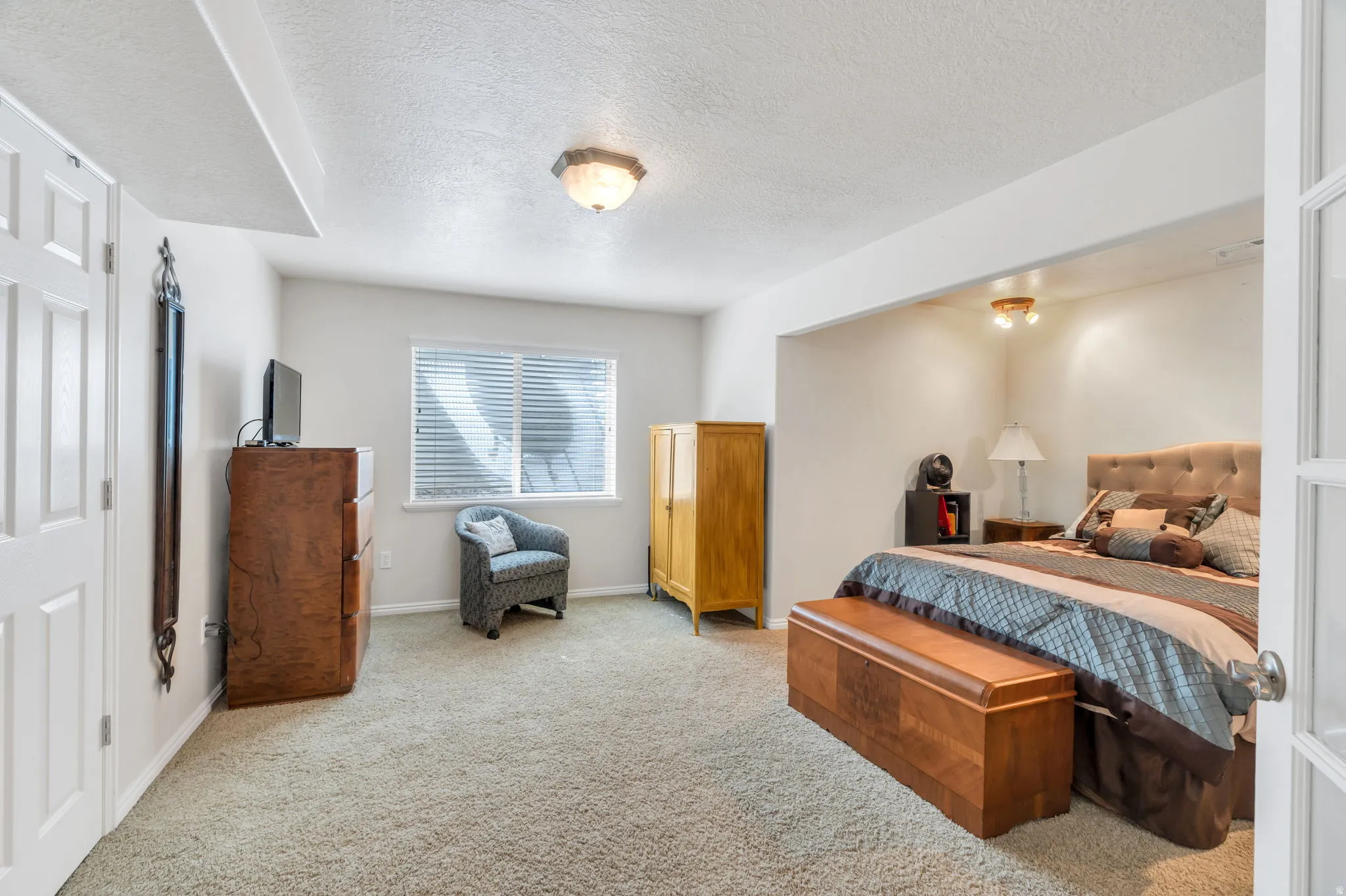 Bedroom featuring light carpet and a textured ceiling