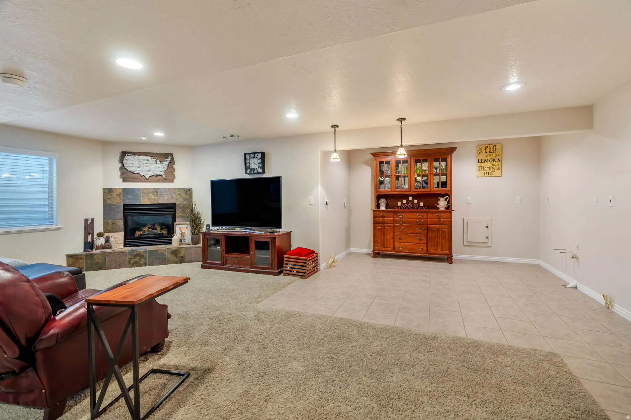 Living area featuring light tile patterned flooring, a tile fireplace, a textured ceiling, light colored carpet, and recessed lighting