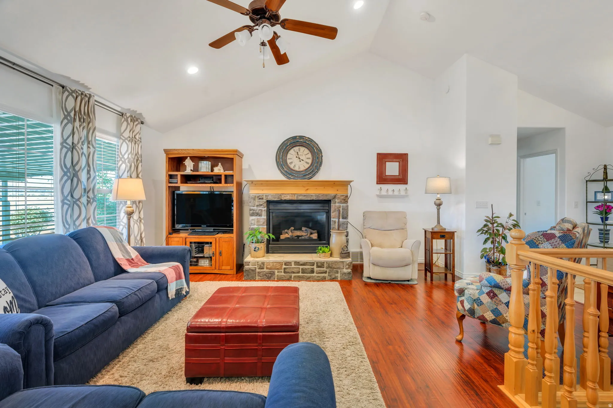 Living room featuring a ceiling fan, lofted ceiling, wood finished floors, recessed lighting, and a fireplace