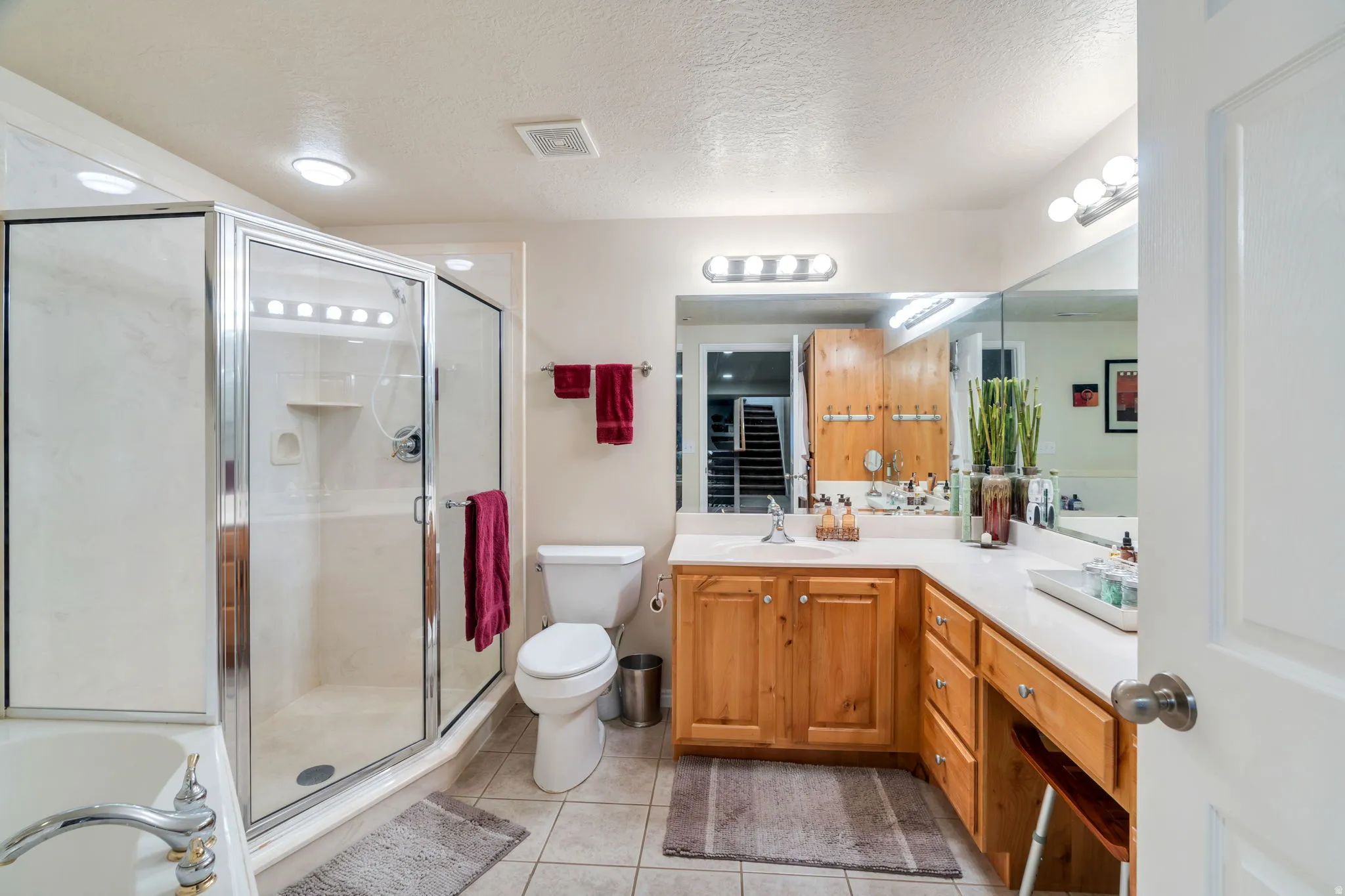 Full bath featuring vanity, a garden tub, a textured ceiling, a stall shower, and light tile patterned floors