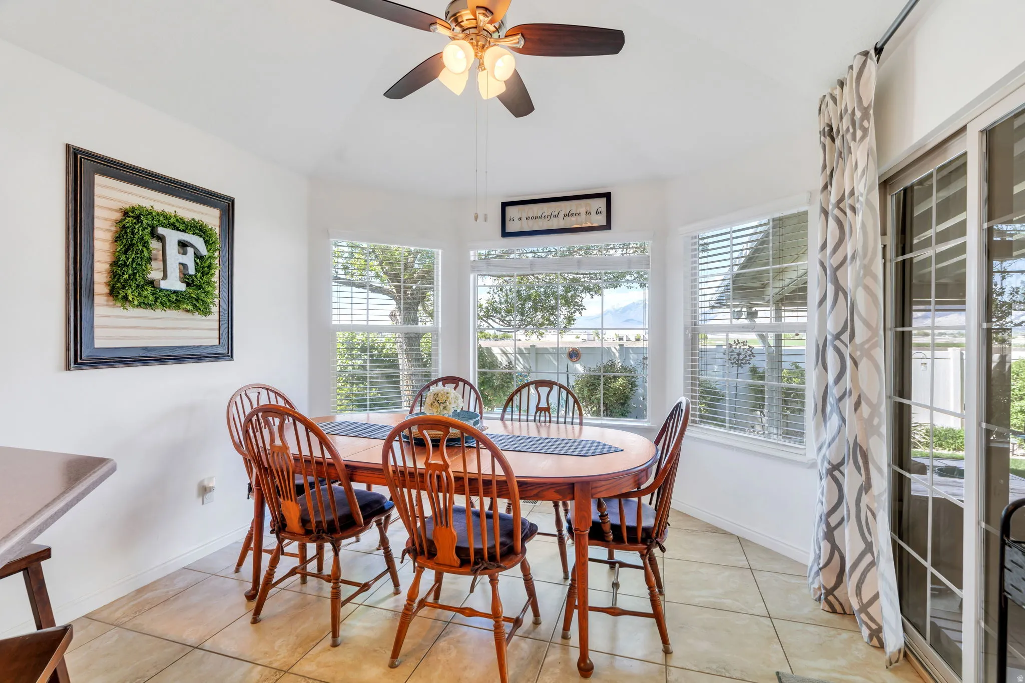 Dining area featuring light tile patterned floors, a ceiling fan, vaulted ceiling, and healthy amount of natural light