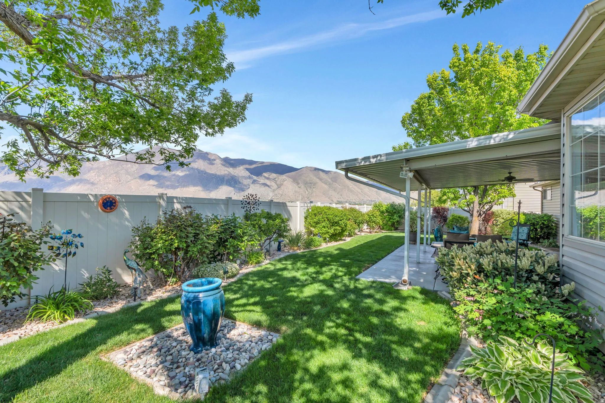 Fenced backyard featuring a ceiling fan, a patio area, and a mountain view