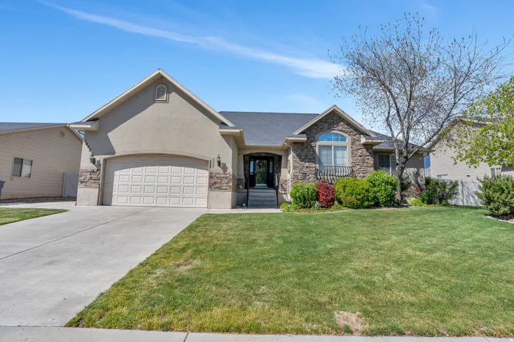 View of front of home featuring stone siding, a garage, concrete driveway, and stucco siding