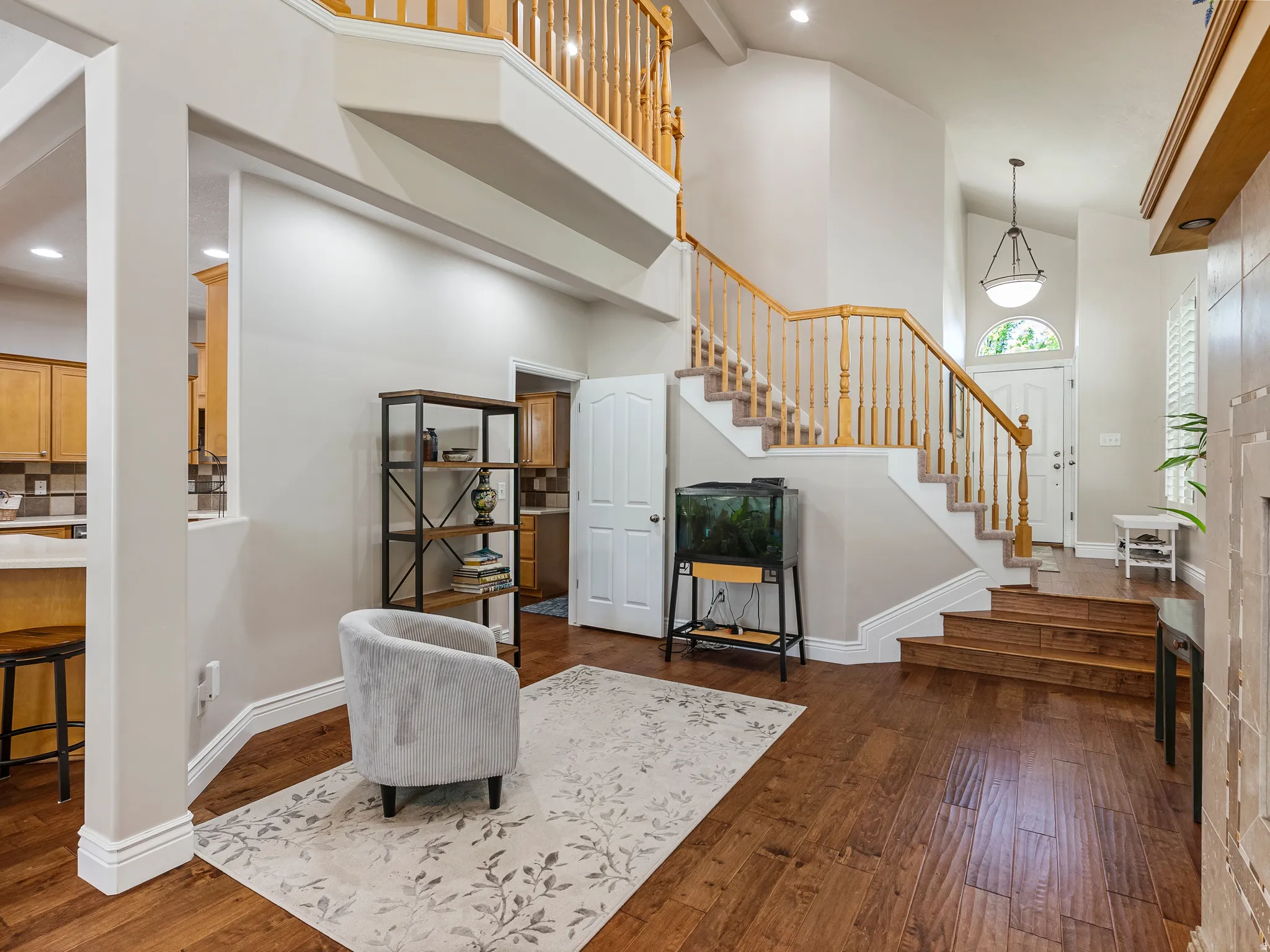 Grand two-story entryway featuring wood-finish flooring, a prominent staircase with wood banisters, and a vaulted ceiling