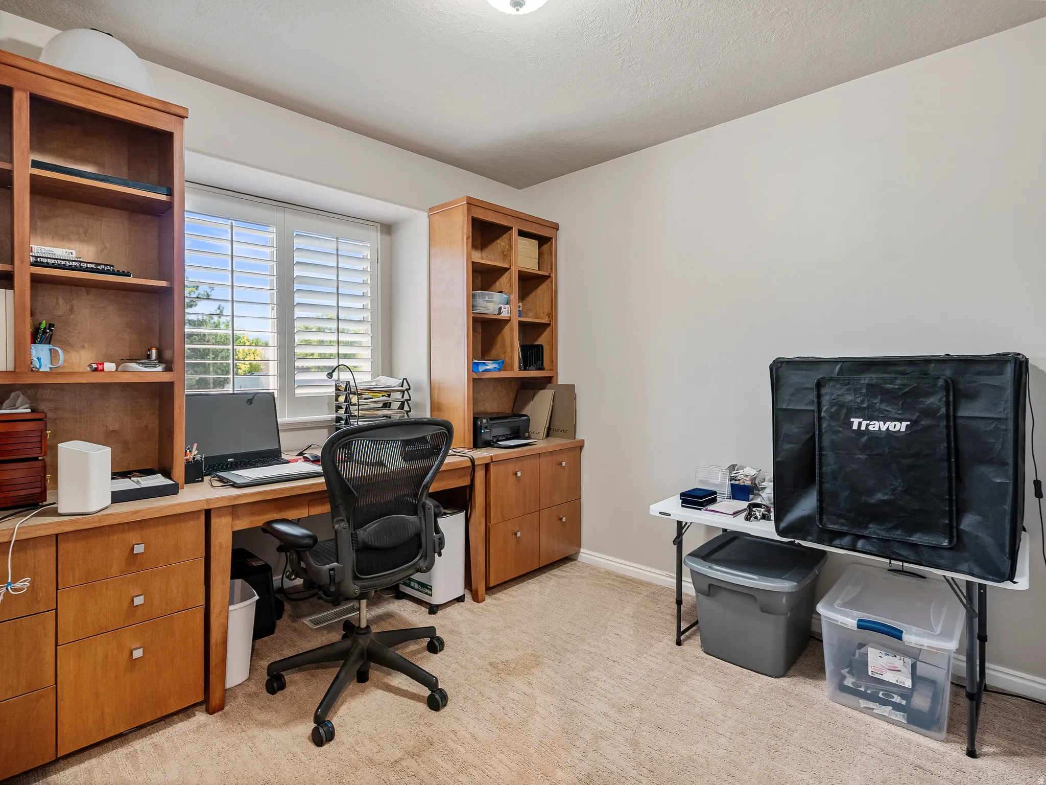 Dedicated room featuring a built-in wood-finish desk, integrated shelving units, and plantation shutters