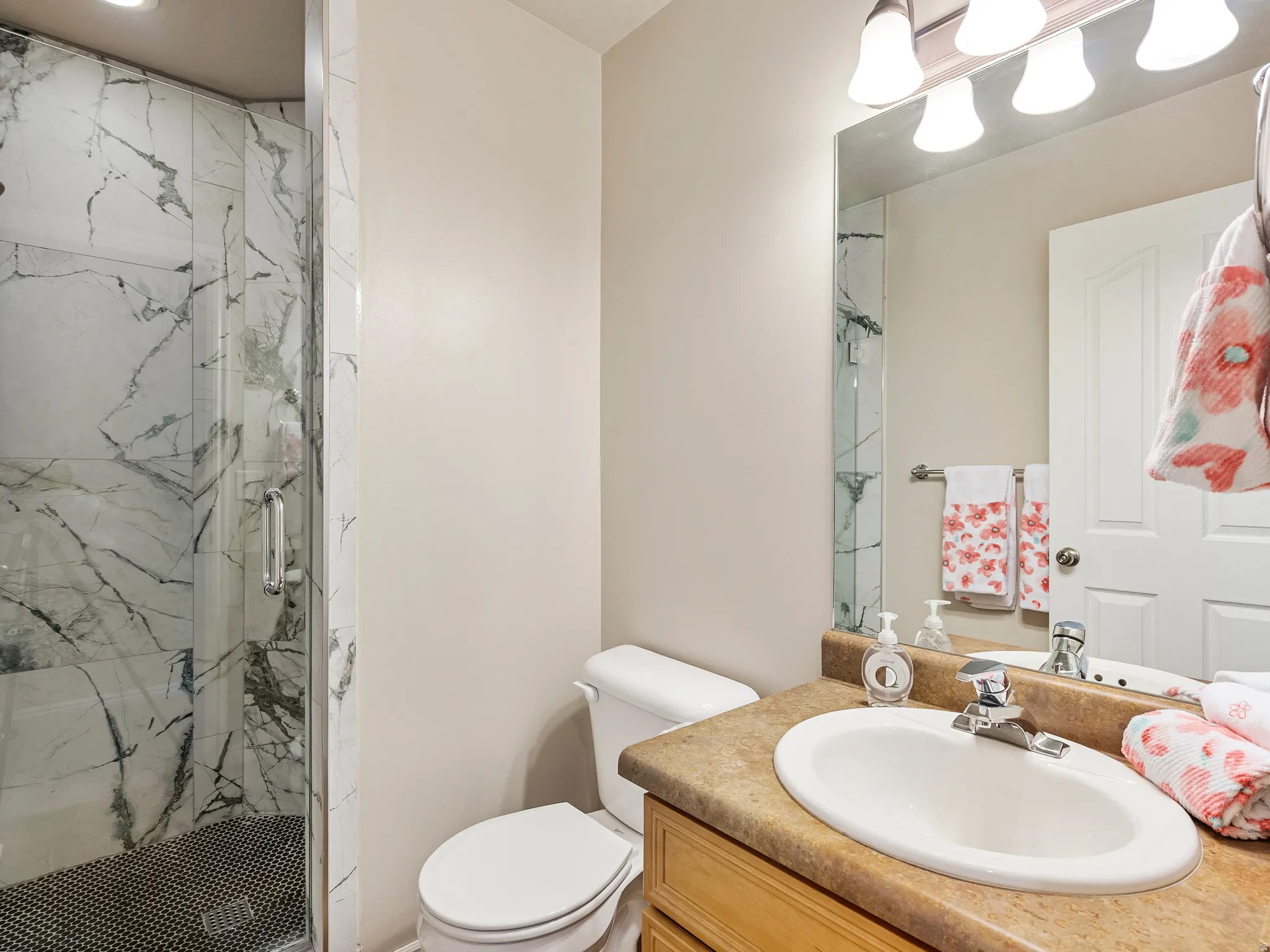 Walk-in shower with clear glass enclosure and marble-look tile surround