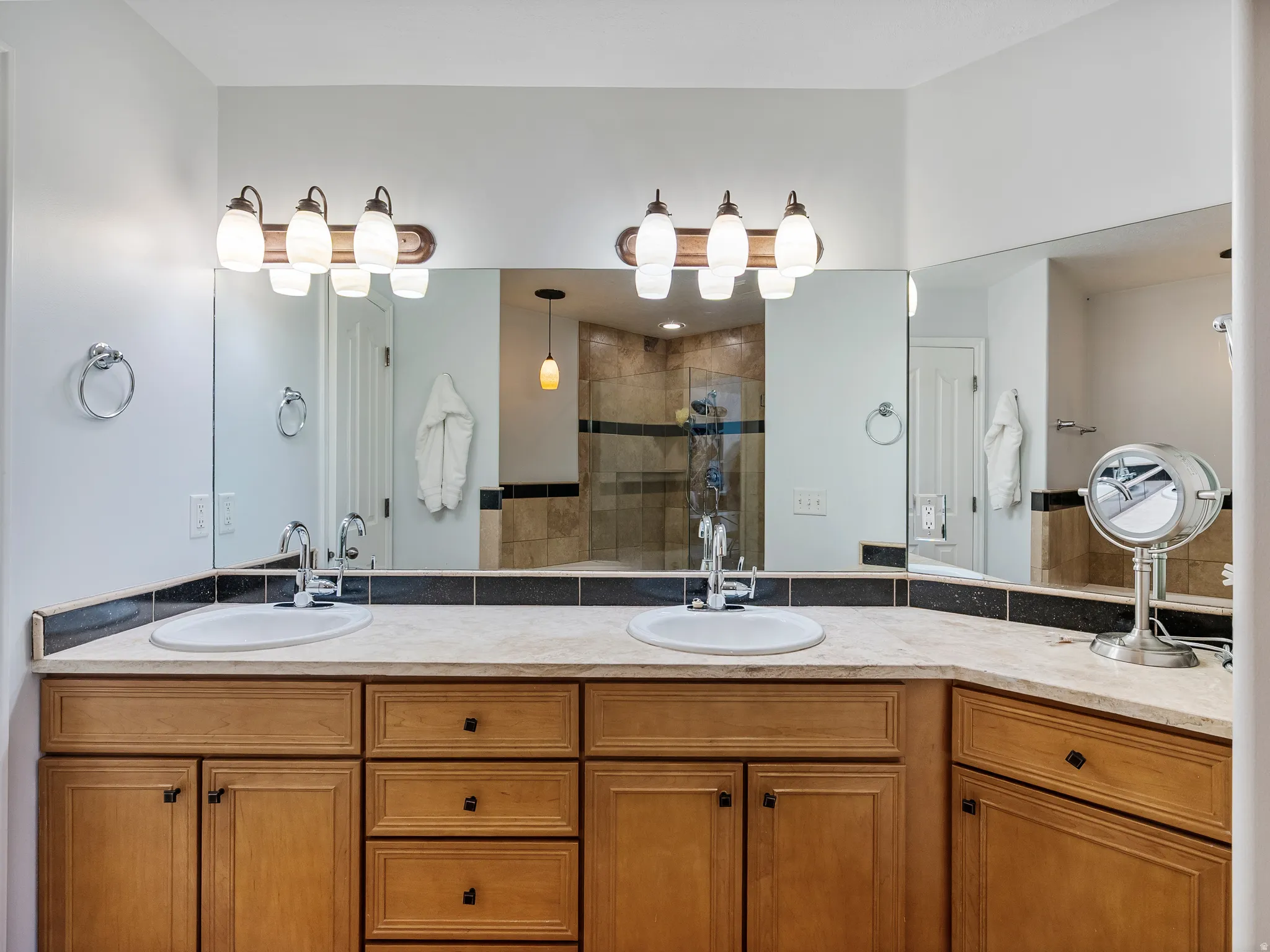 Double vanity with wood-finish cabinetry, light-toned countertop, and undermount sinks