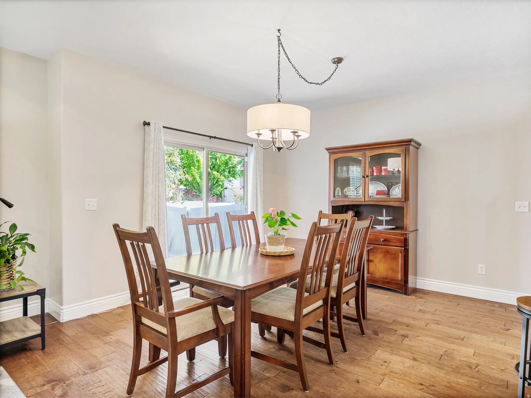 Spacious dining area featuring wood-finish flooring, a contemporary drum chandelier, and a sliding glass door to exterior