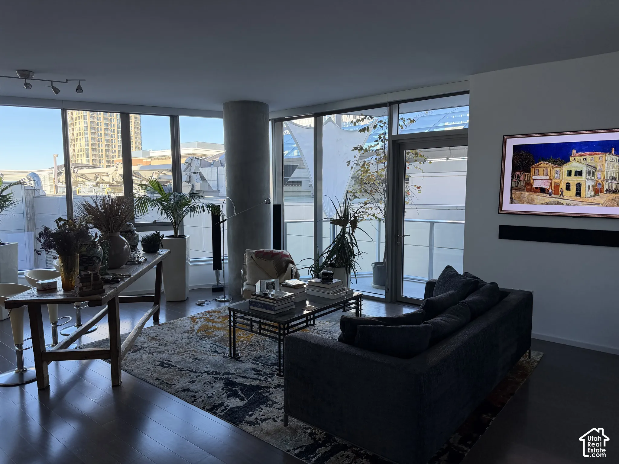 Floor-to-ceiling windows, wood-finish flooring, recessed lighting, and a concrete structural column