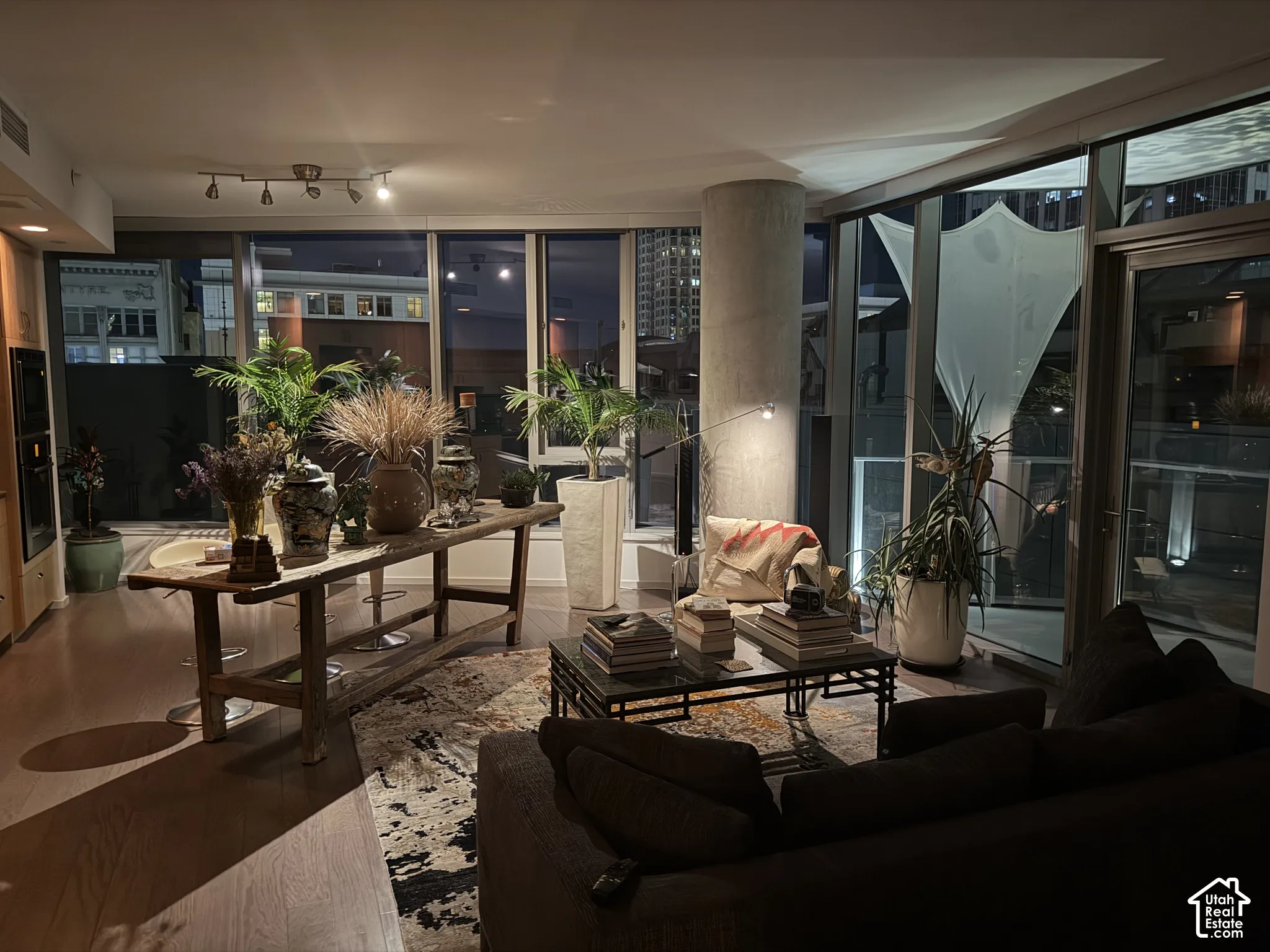 Expansive window walls, wood-finish flooring, recessed lighting, and a prominent concrete structural column