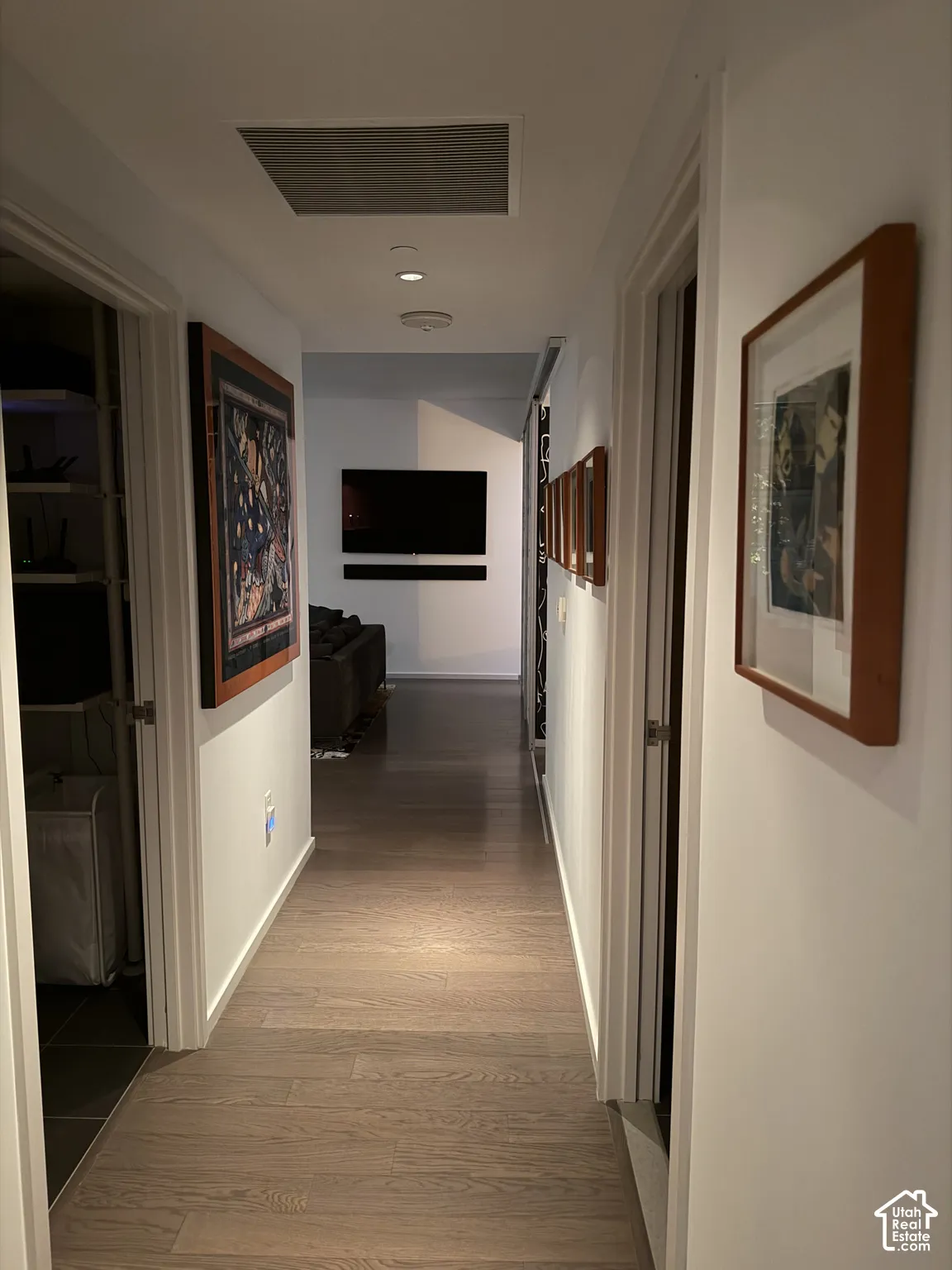 Recessed ceiling lighting illuminates wood-finish flooring throughout the hallway