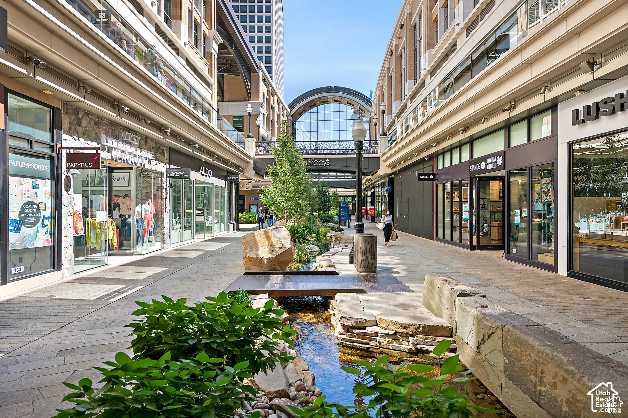 Pedestrian walkway featuring retail storefronts and decorative landscaping