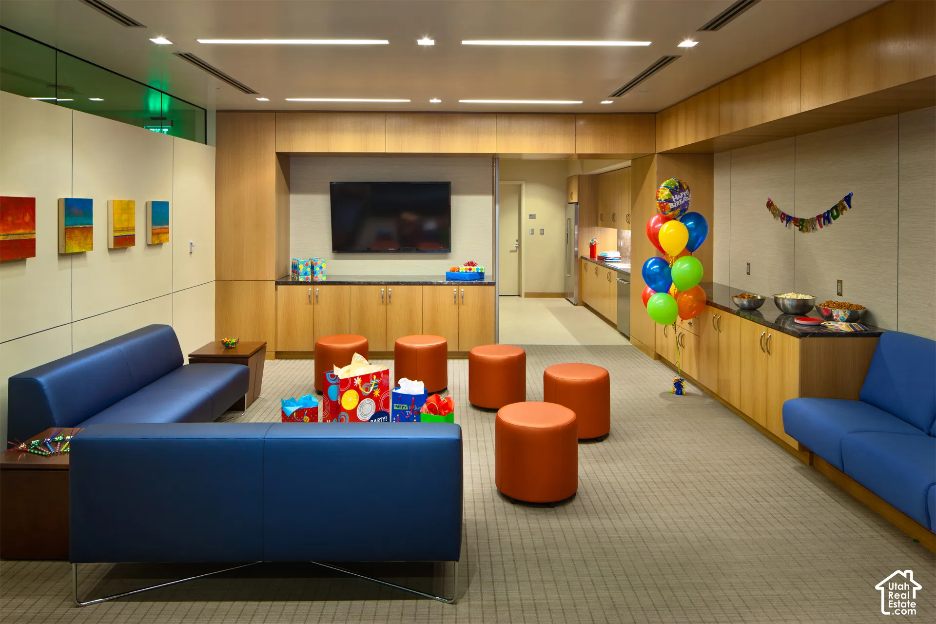 Open-concept common area featuring integrated cabinetry, recessed lighting, wall-mounted television, and a functional kitchenette