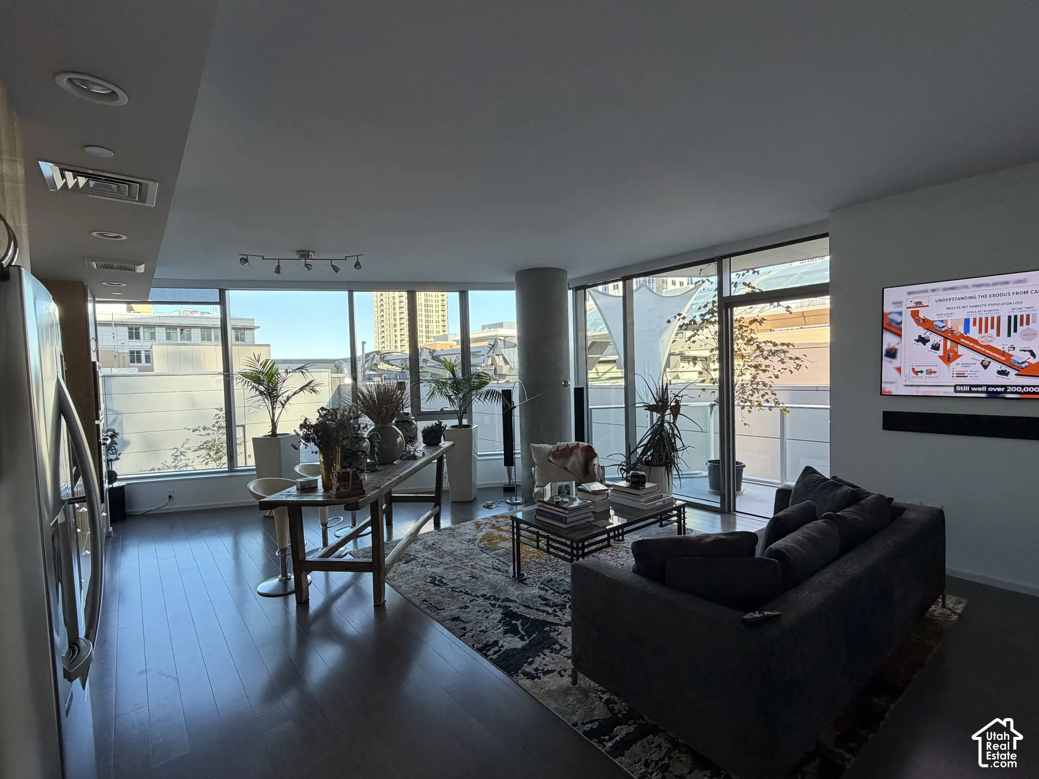 Expansive windows, wood-finish flooring, recessed ceiling lighting, track lighting fixture, and a large sliding glass door opening to an outdoor patio