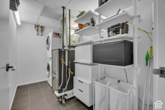 Laundry area featuring stacked washing machine and dryer and dark tile patterned floors
