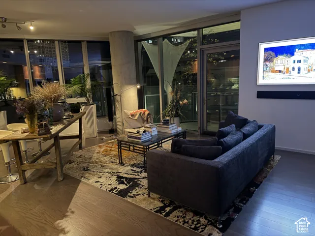 Full-height glass panels, wood-finish flooring, recessed lighting, and a built-in sound bar
