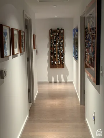 Hardwood-finish flooring, recessed lighting, and white walls define this hallway space