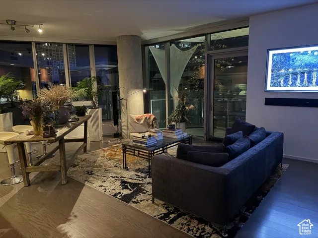 Expansive floor-to-ceiling windows, wood-finish flooring, recessed lighting, and a mounted display screen