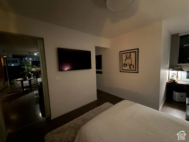 Recessed overhead lighting, dark wood-finish flooring, built-in shelving, and a desk area