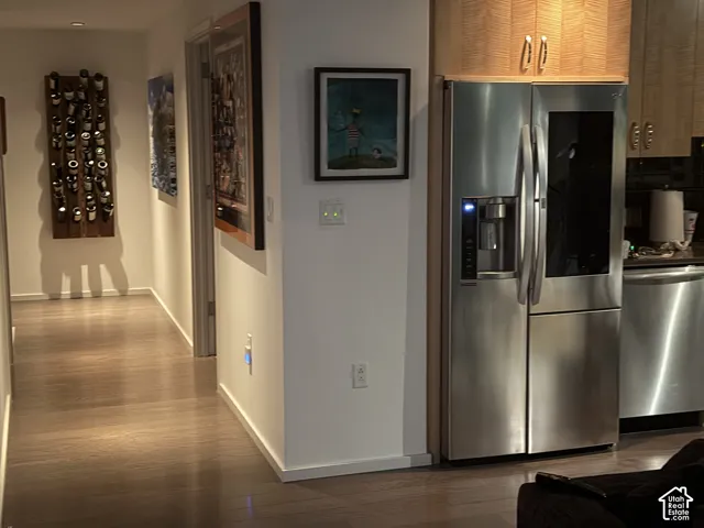 Stainless steel French door refrigerator, wood-finish flooring, and light wood cabinetry with brushed nickel hardware