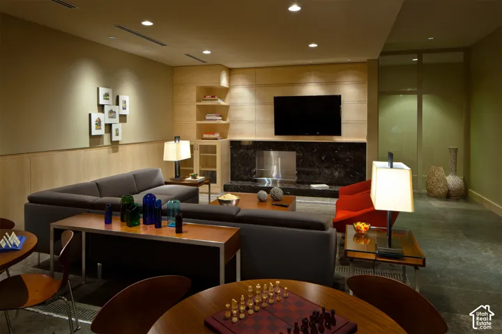 Recessed lighting illuminates a space featuring a central fireplace with a dark stone surround and a built-in television