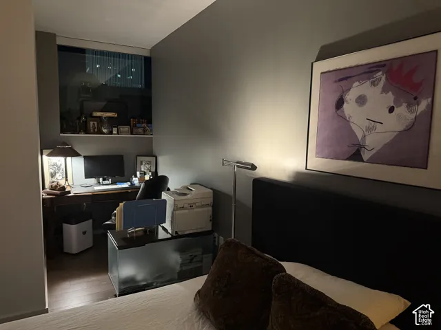 Wall-mounted window offering ambient light, built-in shelving, hardwood flooring, and a dark upholstered headboard