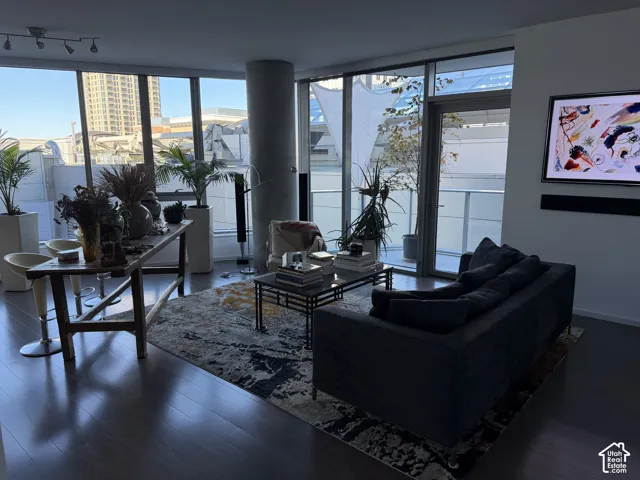 Hardwood-finish flooring, expansive floor-to-ceiling windows, track lighting, private balcony access, and a concrete structural column
