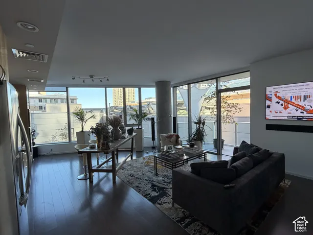 Expansive windows, wood-finish flooring, recessed ceiling lighting, track lighting fixture, and a large sliding glass door opening to an outdoor patio