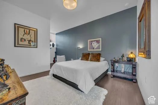 Bedroom with dark wood-style flooring and baseboards
