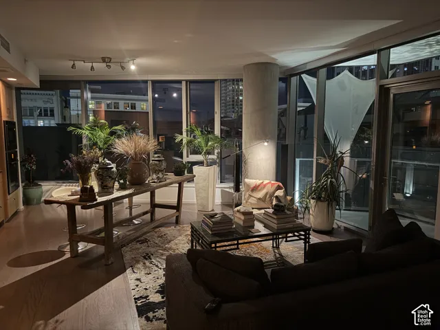 Expansive window walls, wood-finish flooring, recessed lighting, and a prominent concrete structural column