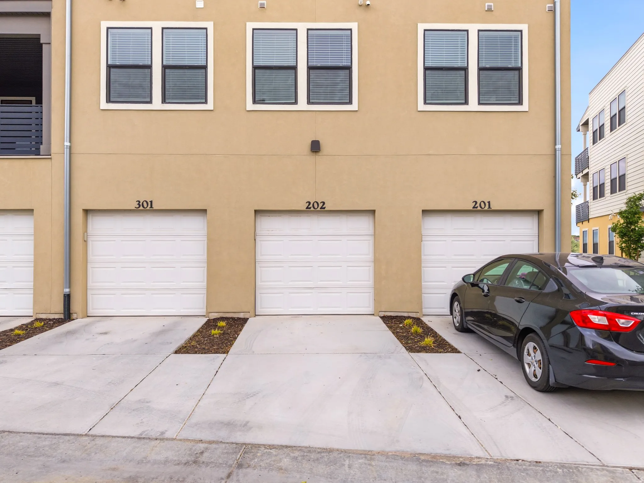 Tan stucco exterior with multiple single-car garage doors