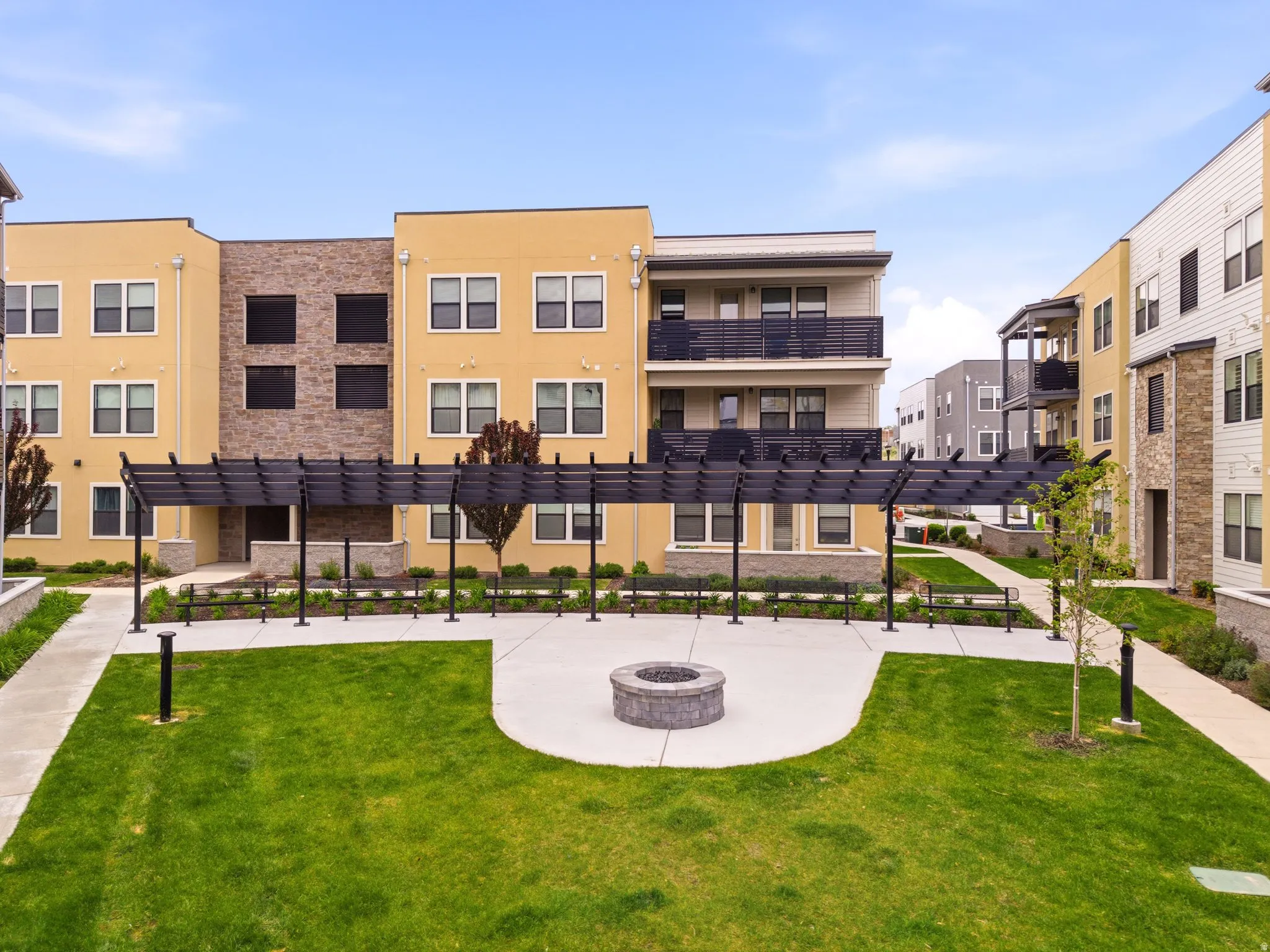 Exterior courtyard featuring a central fire pit, paved patio, and manicured lawn areas